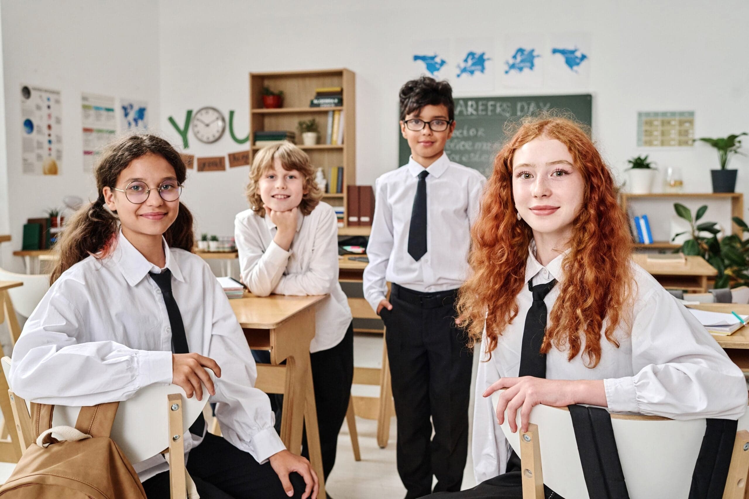 Four smiling primary-school pupils in a bright classroom